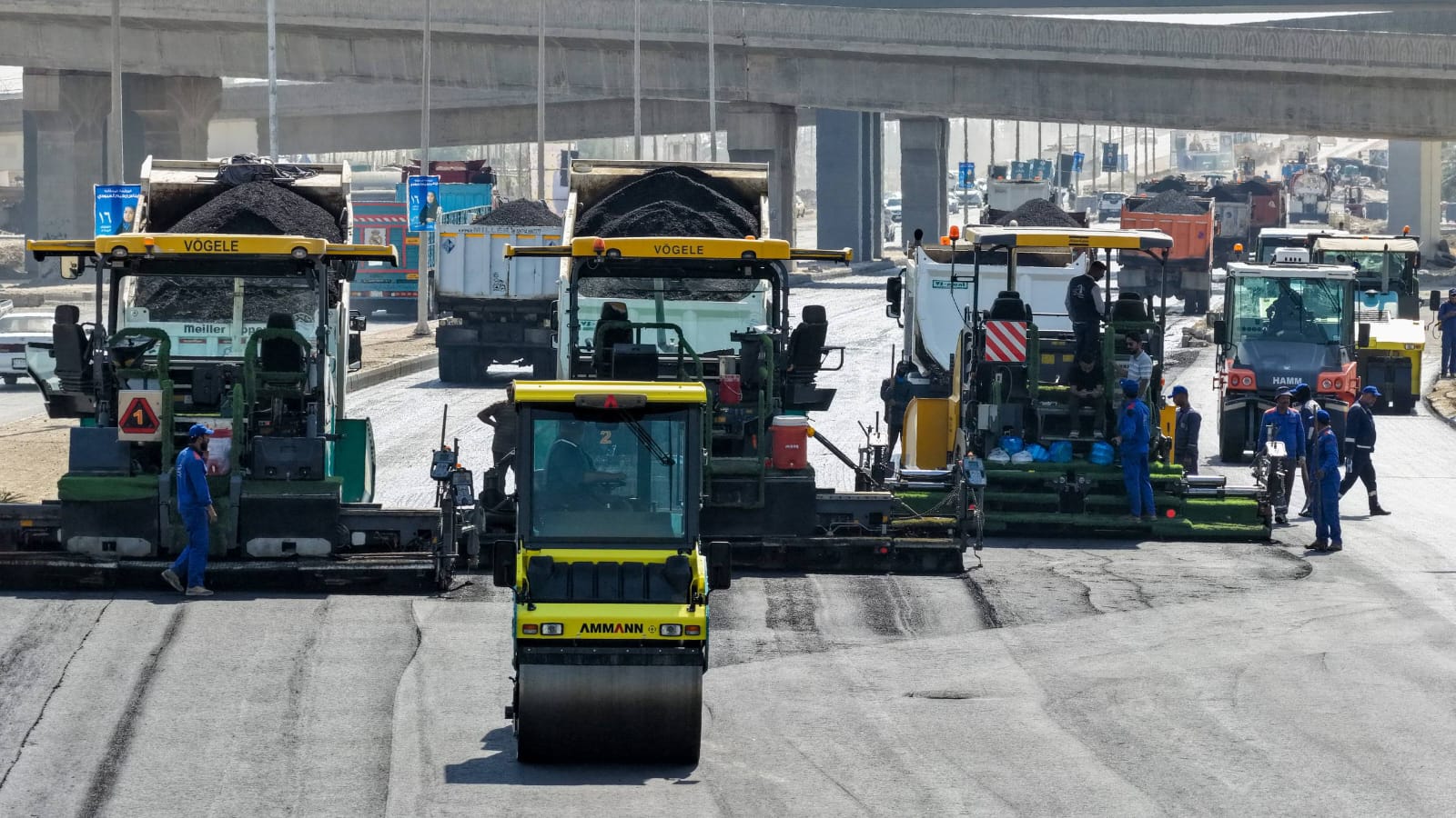 Multiple asphalt pavers and rollers on an AAE road-paving project